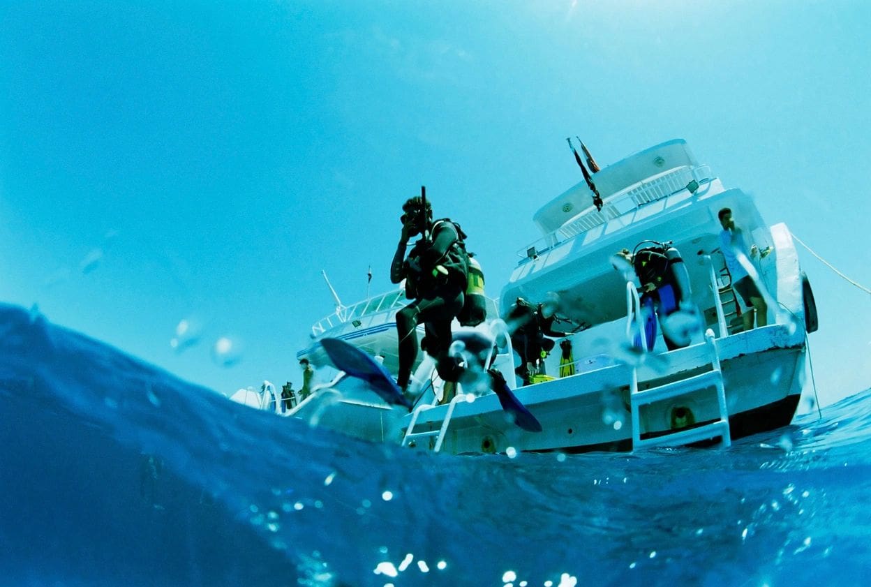 A group of scuba divers on the side of a boat.