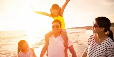 A man and child are standing on the beach.