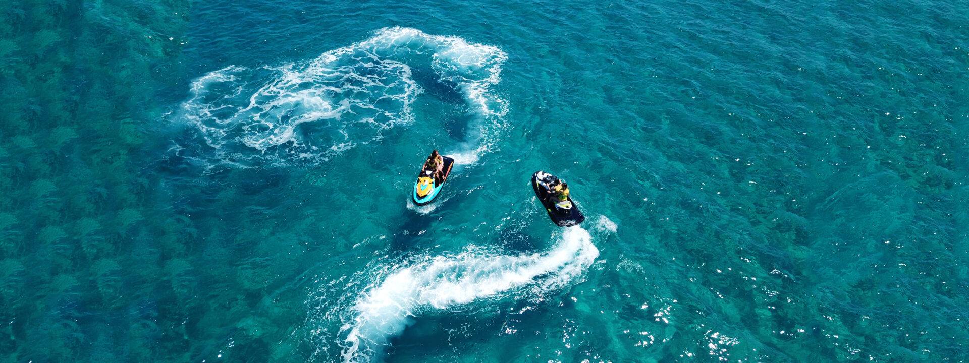 Two people on jet skis in the ocean.