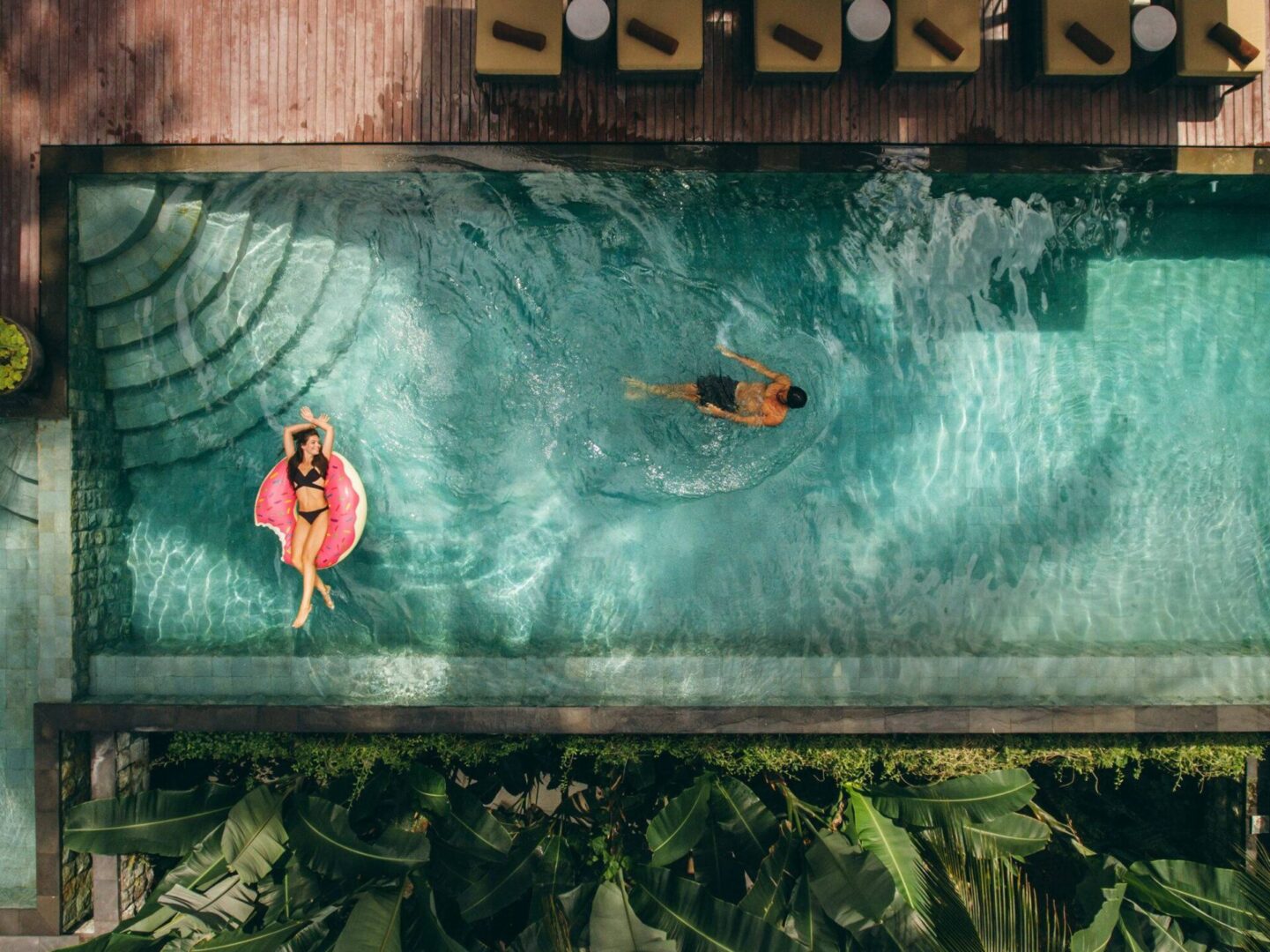 Two people swimming in a pool with plants